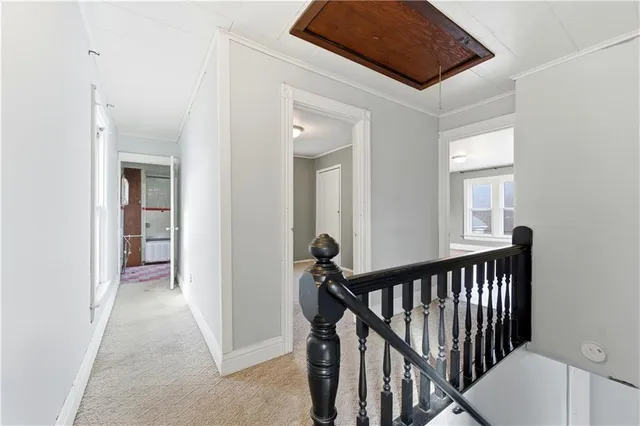 a view of a hallway to a livingroom with wooden floor and staircase