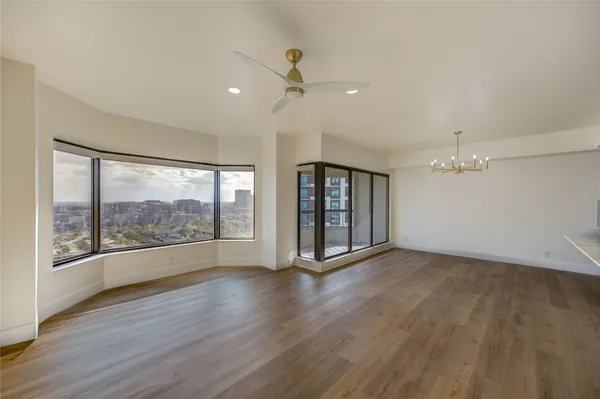 a view of an empty room with a window and wooden floor