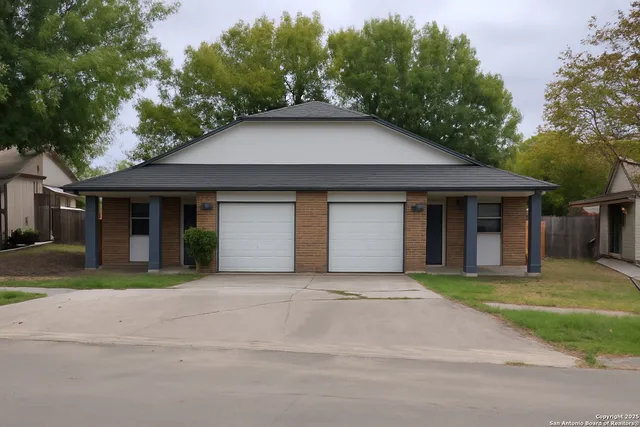 a front view of a house with a garden and trees