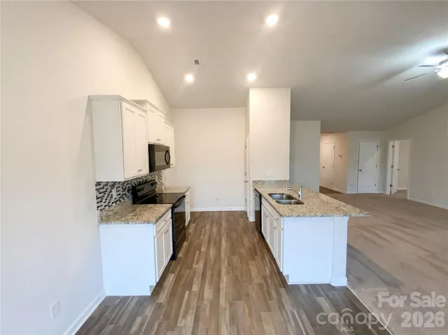 a large kitchen with stainless steel appliances a large counter top a stove and a sink