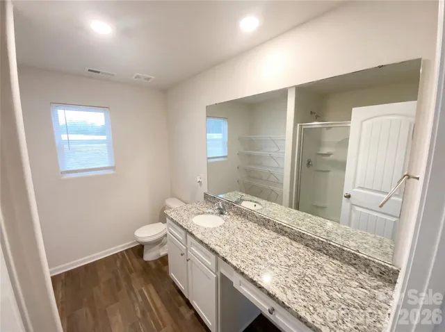 a bathroom with a granite countertop sink a toilet and shower