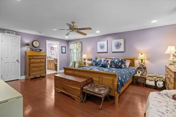a spacious bedroom with a bed and wooden floor