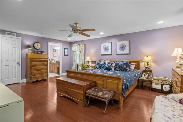 a spacious bedroom with a bed and wooden floor