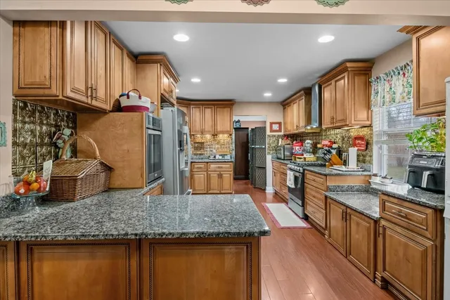 a kitchen with stainless steel appliances granite countertop wooden cabinets and a refrigerator