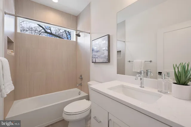a bathroom with a bathtub shower sink vanity mirror and toilet