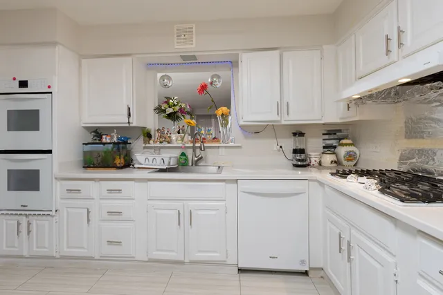 a kitchen with white cabinets and sink