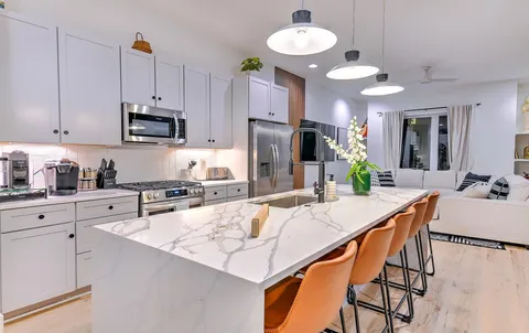 a kitchen with stainless steel appliances kitchen island granite countertop a refrigerator a stove a microwave oven with a dining table and chairs