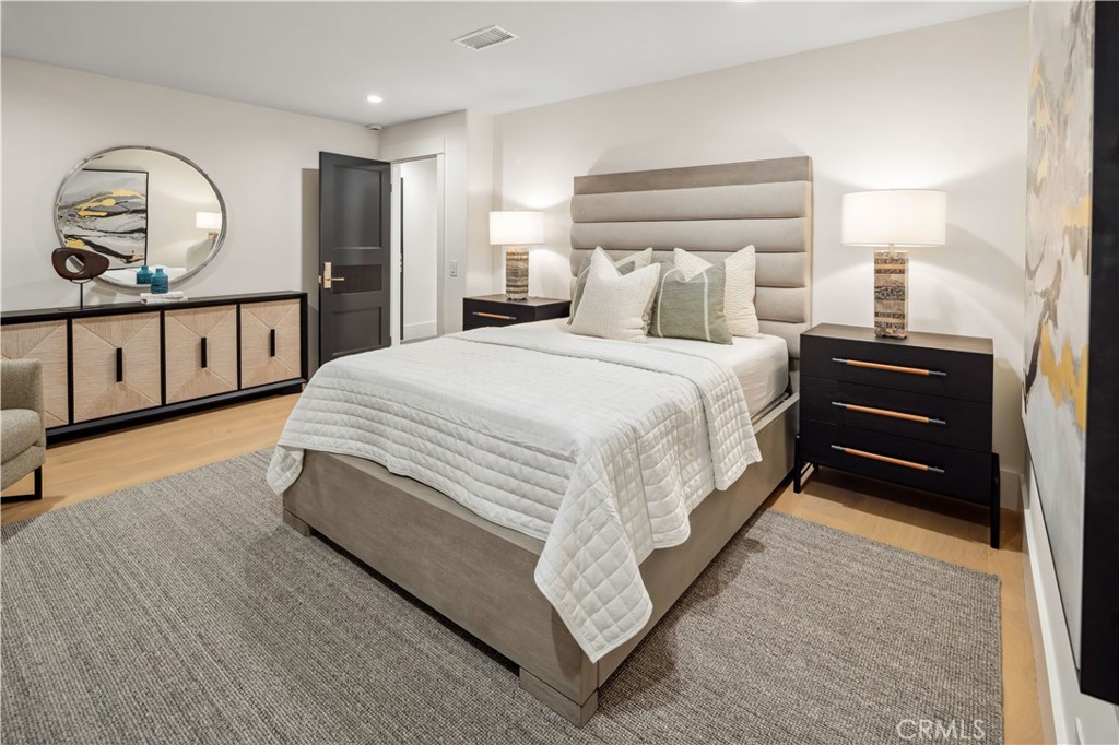 2915 Cliff Drive Newport Beach, CA 92663 - Photo 62 of 69 a spacious bedroom with a bed a mirror on dresser and a chandelier