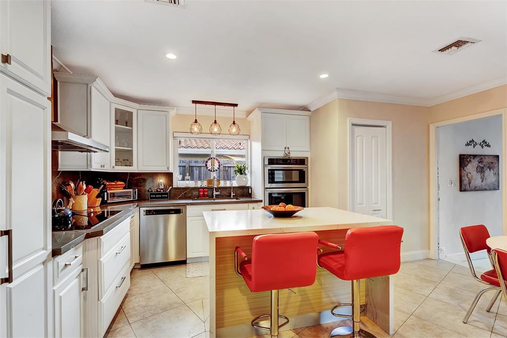 1500 Northeast 24th Street Wilton Manors, FL 33305 - Photo 30 of 88 a kitchen with stainless steel appliances kitchen island granite countertop a stove and cabinets
