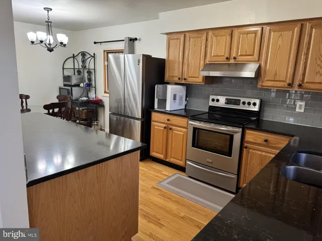 a kitchen with stainless steel appliances granite countertop a refrigerator a stove a sink and a microwave