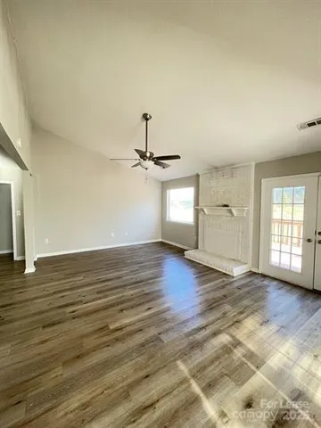 an empty room with wooden floor cabinet and windows