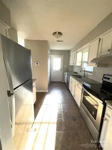 a large kitchen with stainless steel appliances granite countertop a refrigerator and a sink