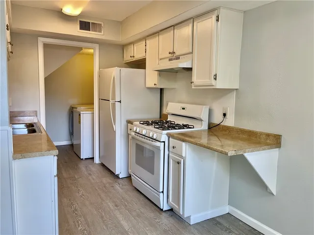 a kitchen with stainless steel appliances white cabinets and wooden floor