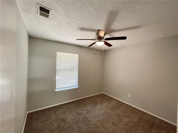 an empty room with a window and a fan