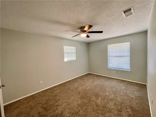 an empty room with windows and chandelier fan
