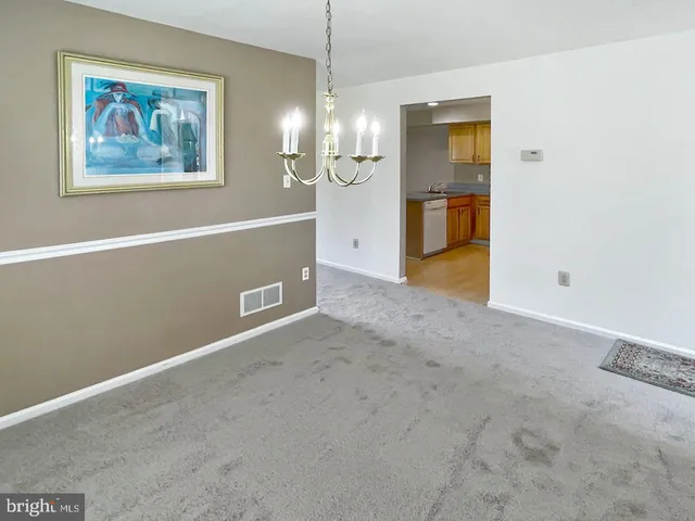 a view of a hallway with wooden floor and a kitchen