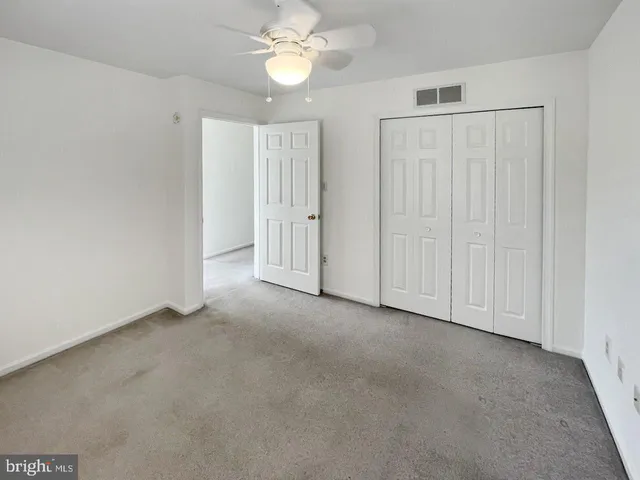 a view of an empty room and chandelier fan
