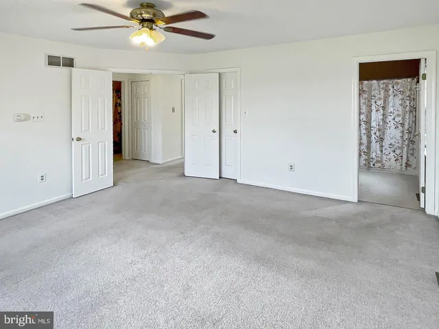 an empty room with windows and fan