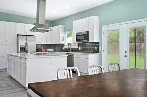 a kitchen with stainless steel appliances granite countertop a stove a sink a refrigerator and white cabinets