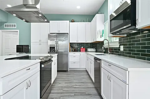 a kitchen with kitchen island granite countertop a sink appliances cabinets and a counter top space