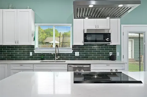 a kitchen with granite countertop white cabinets and a stove top oven