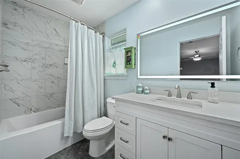 a bathroom with a granite countertop sink a toilet and a bathtub