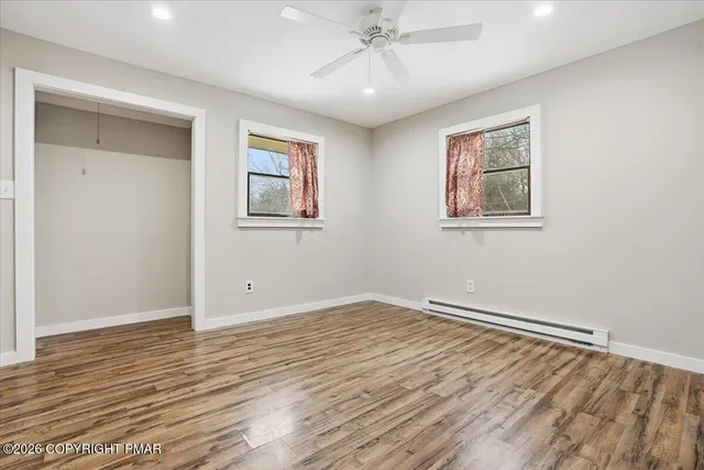 a view of empty room with wooden floor and fan