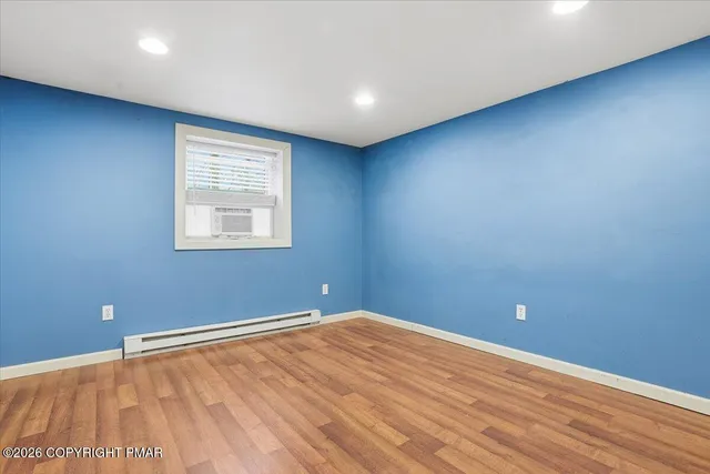 a view of an empty room with wooden floor and closet