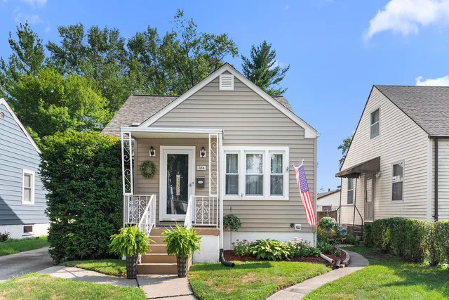 a view of a house with brick walls and a yard with plants and large trees