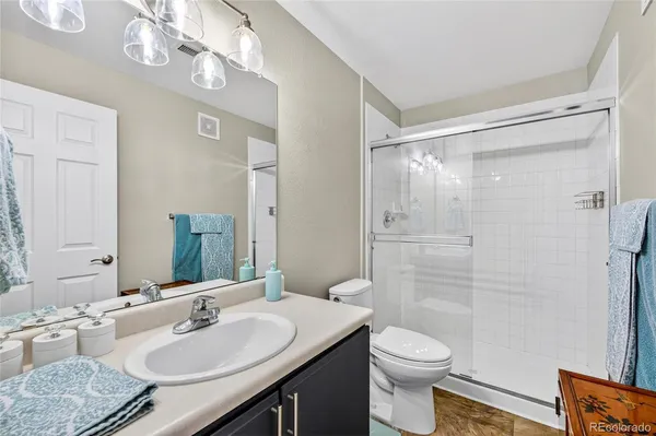 a bathroom with a granite countertop sink toilet a mirror a vanity and shower