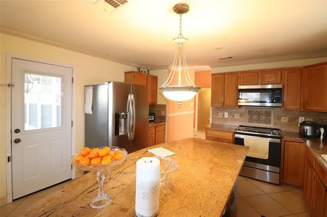 a kitchen with stainless steel appliances kitchen island granite countertop a refrigerator a stove and a sink with granite countertops