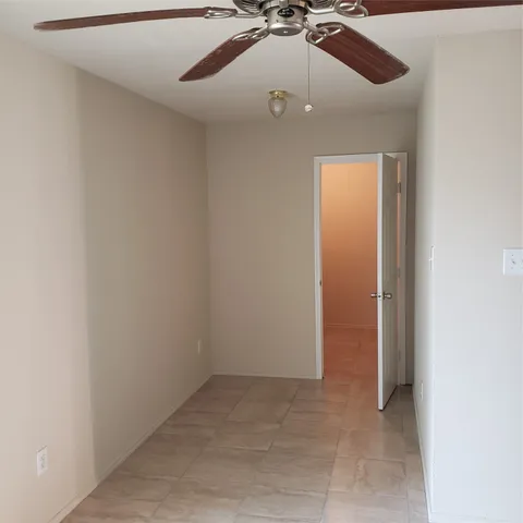 an empty room with a ceiling fan and carpet