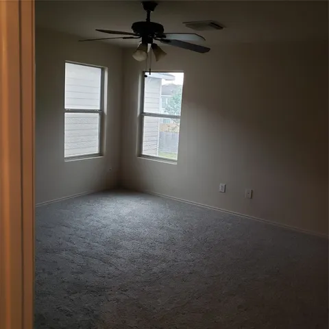 an empty room with windows and a ceiling fan