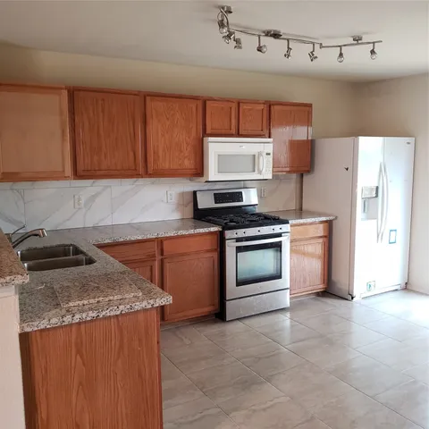 a kitchen with stainless steel appliances granite countertop a stove a sink and a refrigerator