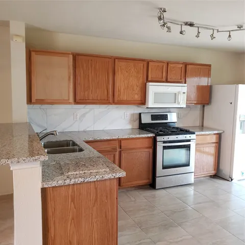 a kitchen with stainless steel appliances granite countertop a stove a sink and a refrigerator