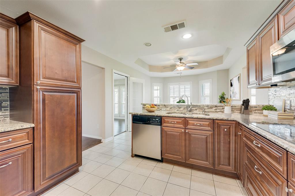 11374 Jennifer Circle Forney, TX 75126 - Photo 15 of 36 Kitchen featuring backsplash, light stone counters, stainless steel appliances, a raised ceiling, and a peninsula.