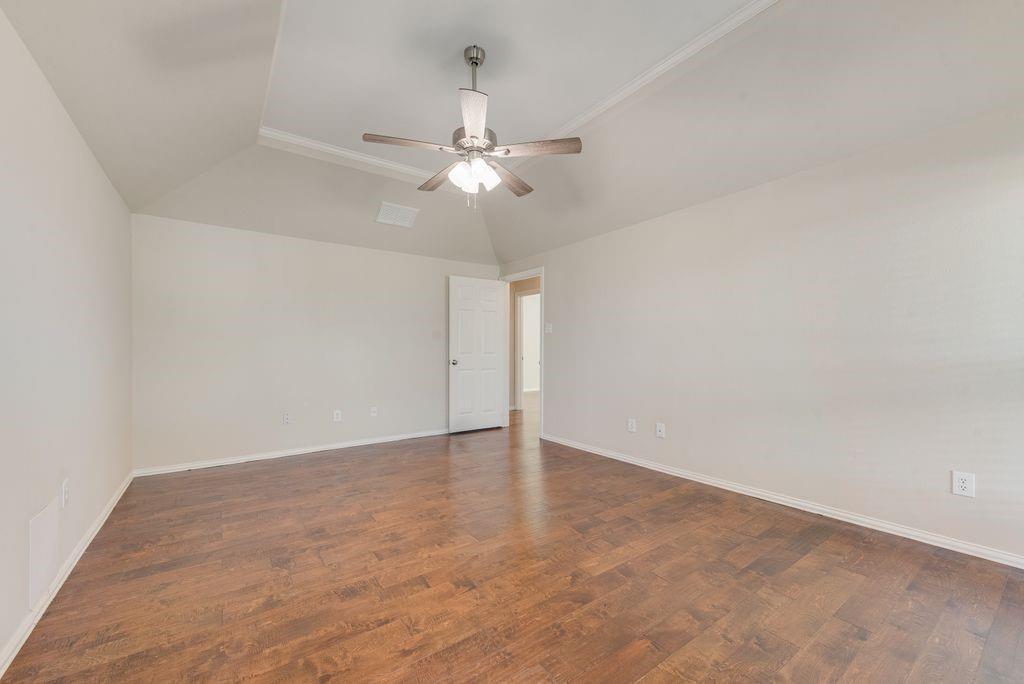 11374 Jennifer Circle Forney, TX 75126 - Photo 26 of 36 Master bedroom featuring dark wood flooring, ceiling fan, ornamental molding, and lofted ceiling.