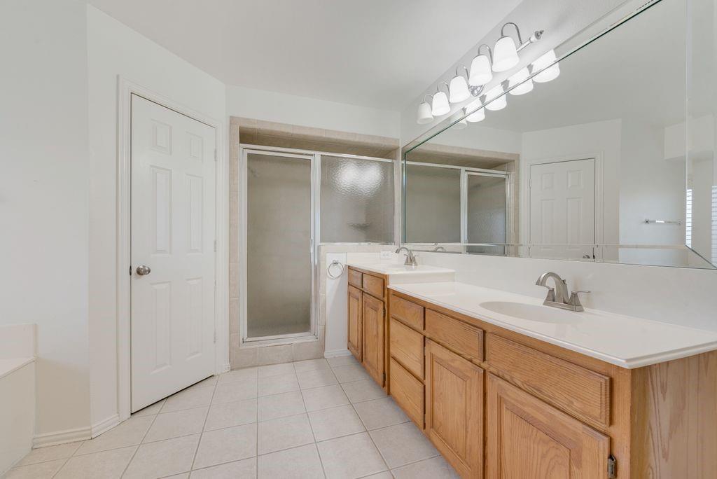 11374 Jennifer Circle Forney, TX 75126 - Photo 30 of 36 Full bath featuring double vanity, light tile patterned floors, a garden tub, and a stall shower.