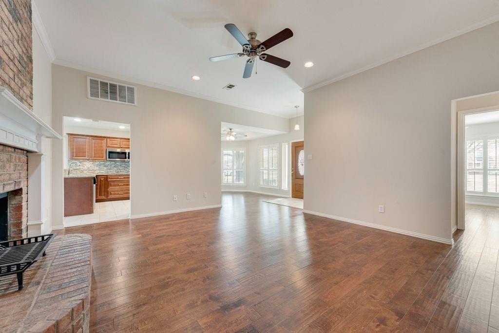 11374 Jennifer Circle Forney, TX 75126 - Photo 6 of 36 Spacious family room with crown molding, rich wood flooring, and a cozy brick fireplace, flowing into a light filled front dining area with an open, airy feel.