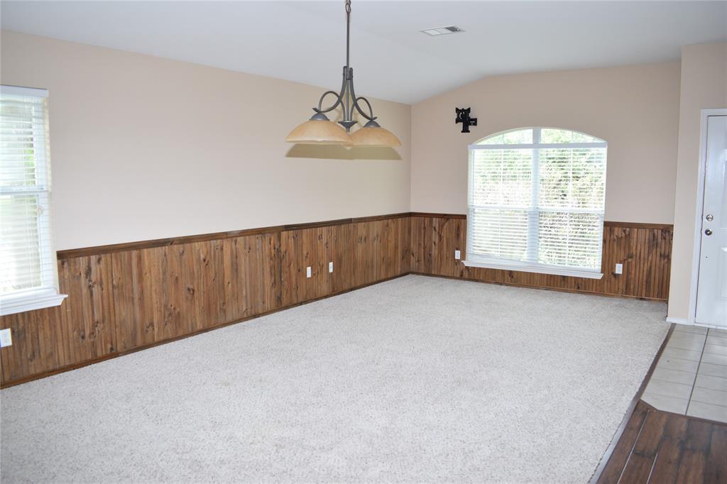 3688 Spring Canyon Trail Round Rock, TX 78681 - Photo 3 of 17 Carpeted living space featuring wood paneling wainscoting, an arched window, and a decorative chandelier
