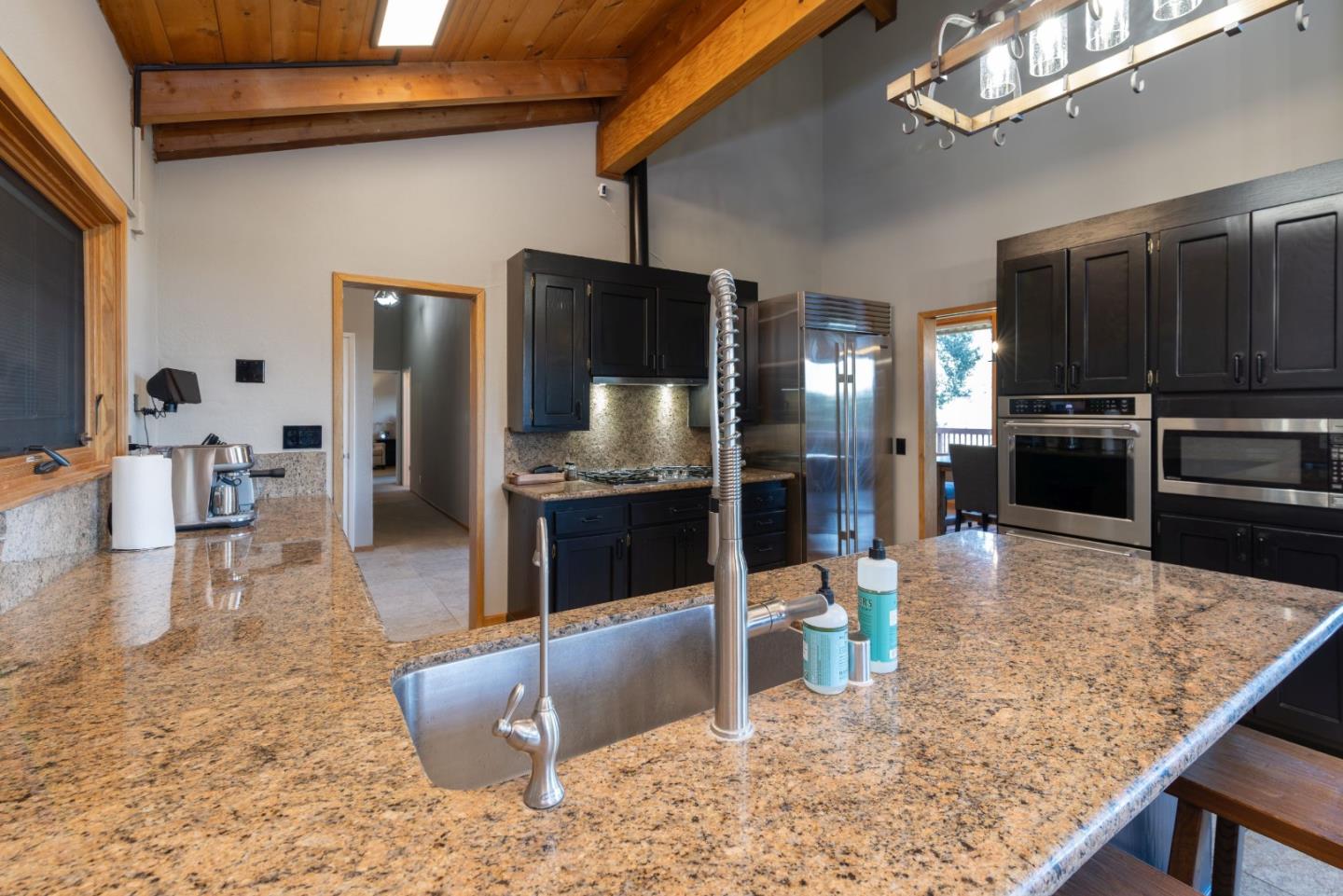 22125 Miller Ridge Road Los Gatos, CA 95033 - Photo 17 of 35 a kitchen with stainless steel appliances kitchen island granite countertop a refrigerator a stove and a sink with wooden floor