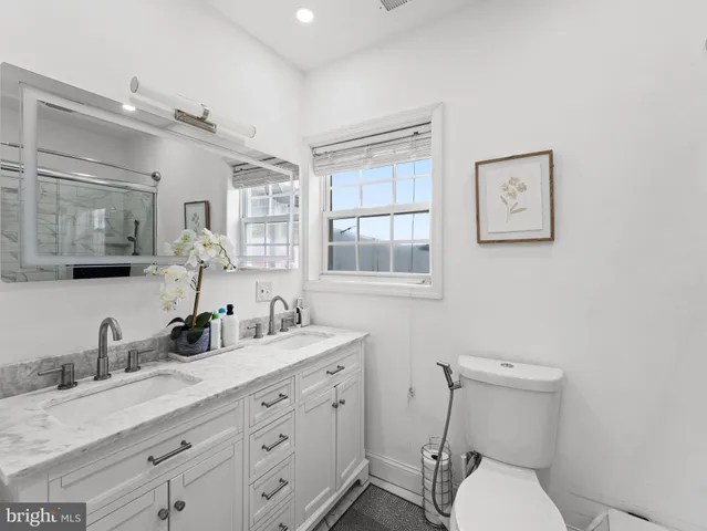 a bathroom with a granite countertop toilet sink and mirror
