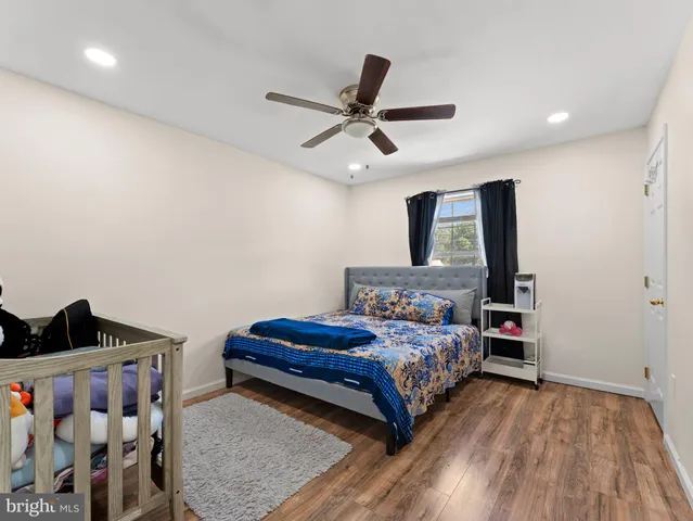 a bedroom with a bed and a dresser with wooden floor