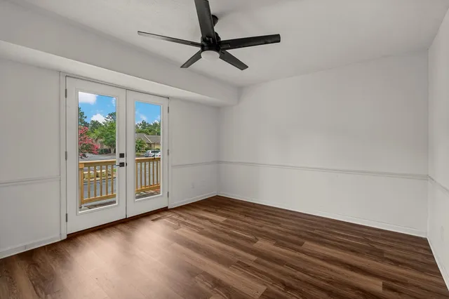 a view of an empty room with wooden floor and a window