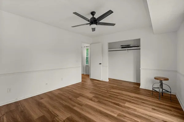 a view of empty room with wooden floor and ceiling fan