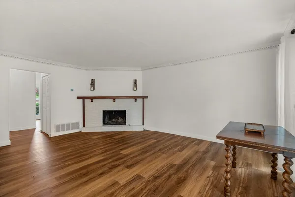a view of empty room with wooden floor and fireplace