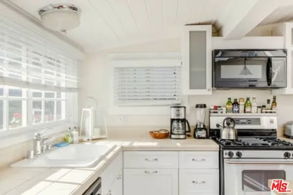 a kitchen with granite countertop a sink stainless steel appliances and cabinets