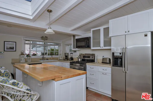 a kitchen with stainless steel appliances granite countertop a refrigerator a sink dishwasher a stove top oven a dining table and chairs with wooden floor