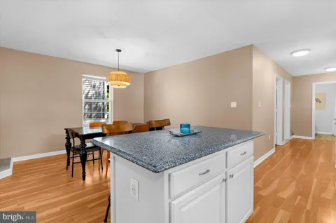 a kitchen with stainless steel appliances kitchen island granite countertop a refrigerator a stove a sink a dining table and chairs