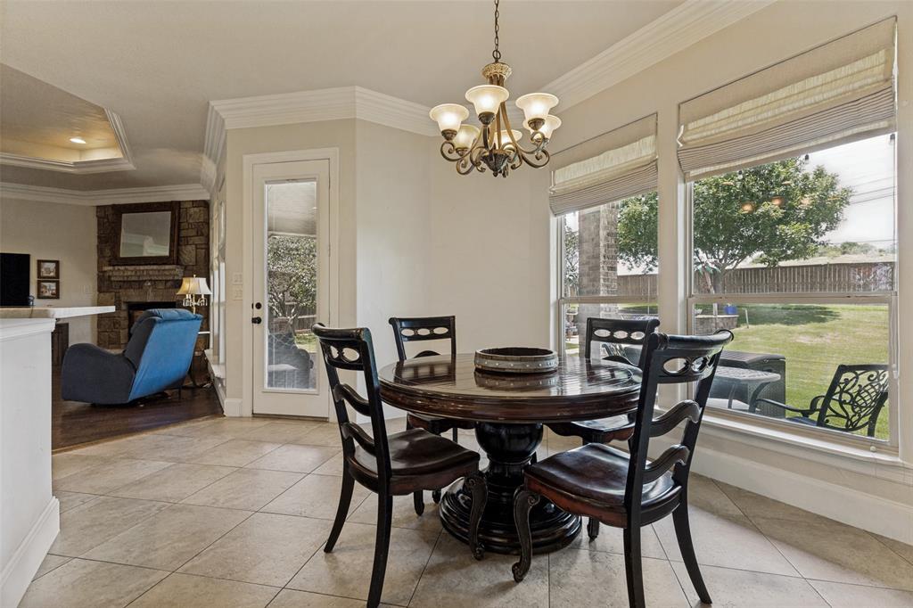 229 Arbor Lane Haslet, TX 76052 - Photo 11 of 34 Breakfast nook featuring large windows, a glass-paned exterior door, crown molding, a built-in stone fireplace, and a tray ceiling